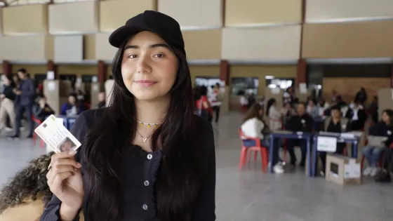 Joven muestra su documento de identidad en un puesto de votación durante la jornada electoral en Colombia. La fotografía ilustra la convocatoria de la Registraduría Nacional para que más de 11 millones de jóvenes participen en las elecciones de los Consejos de Juventud.