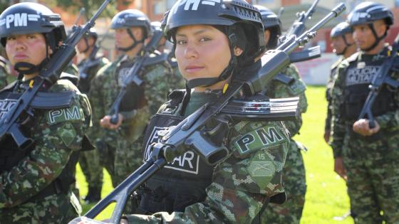 Oficial del Ejército en formación militar, acompañada de otros soldados